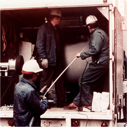 Workmen unreeling optical cable from reel in back of truck